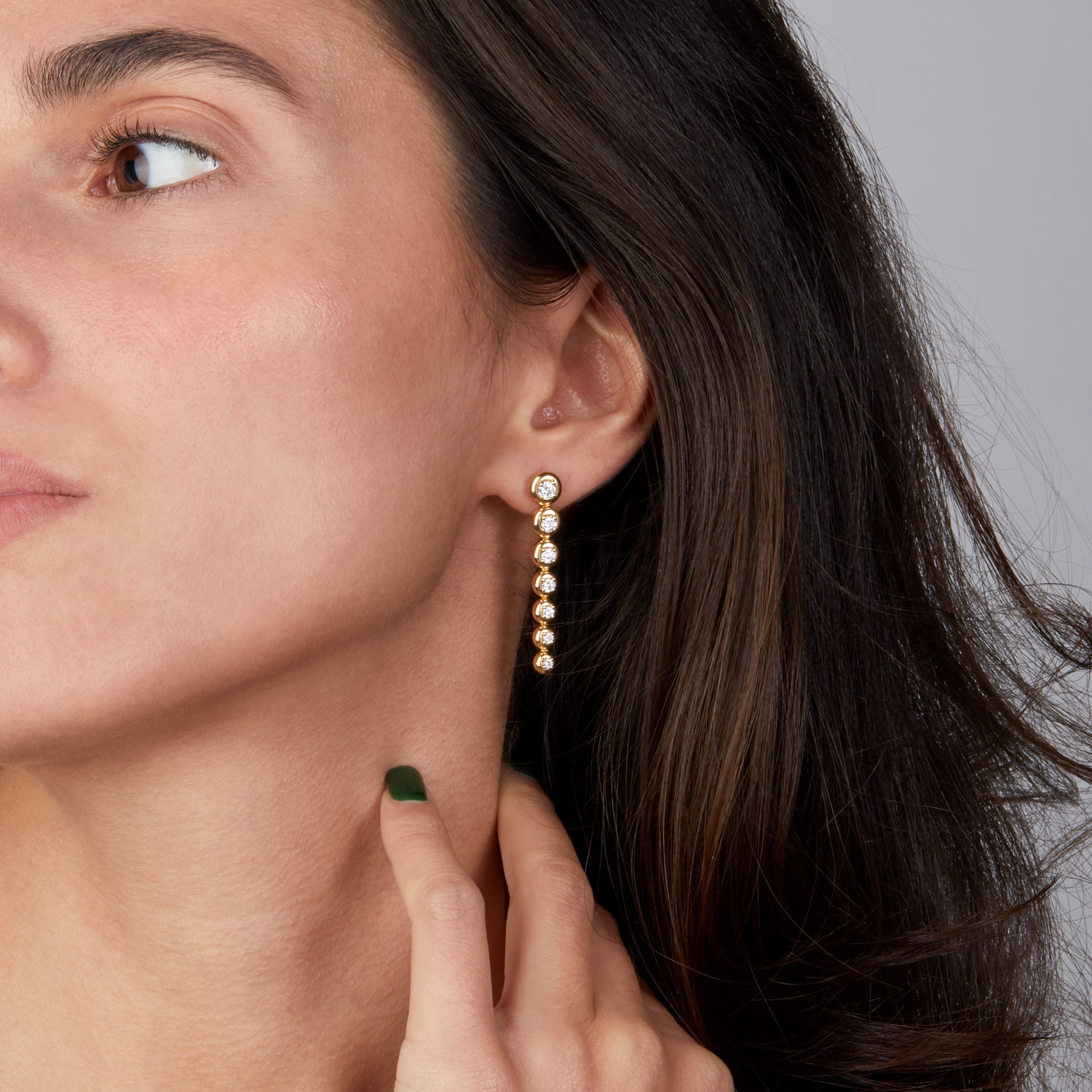 Star trail yellow gold earrings with diamonds displayed on model.