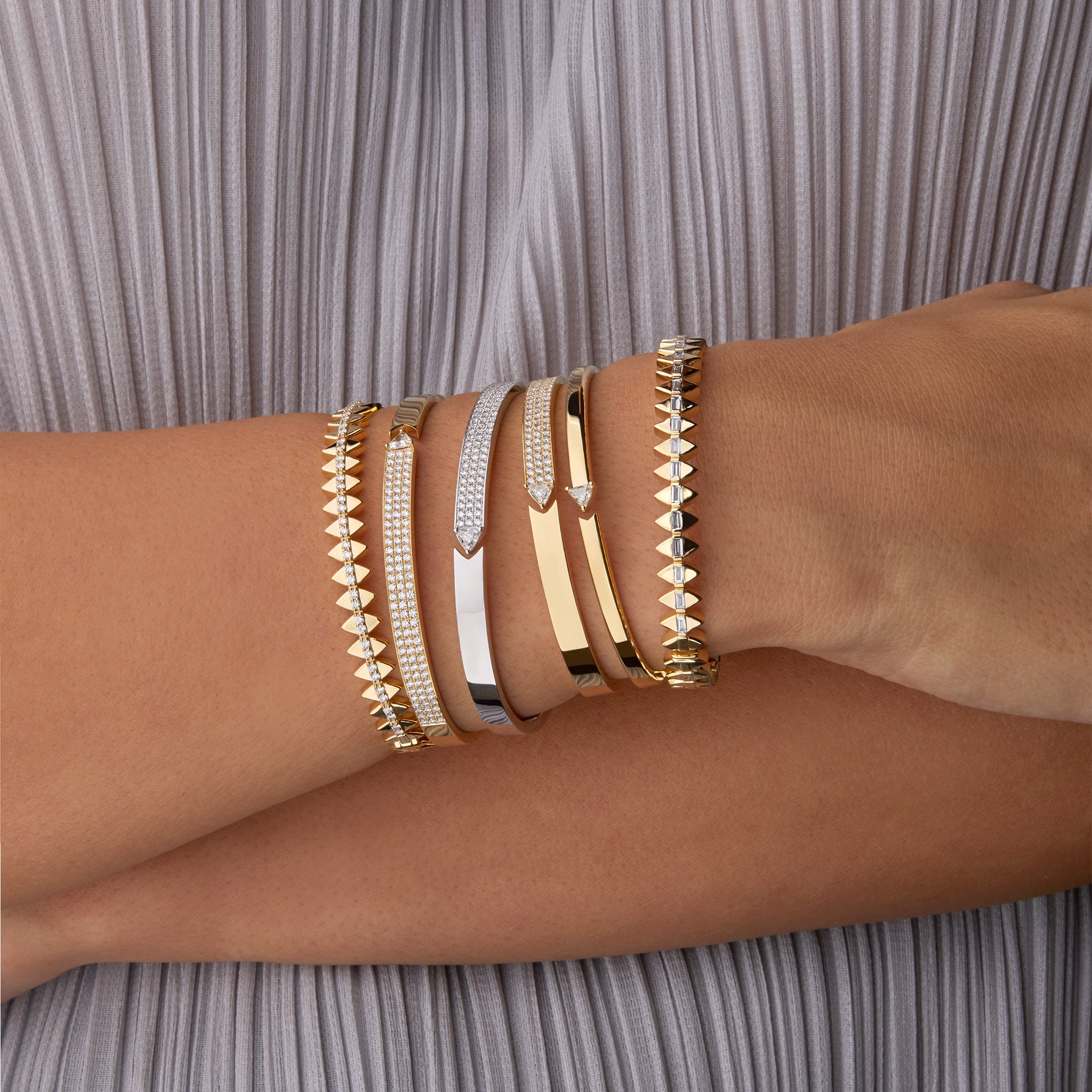 Stack of Stellar Standstill and Solidarity bangle in yellow and white gold featuring diamonds  displayed on hand model. 